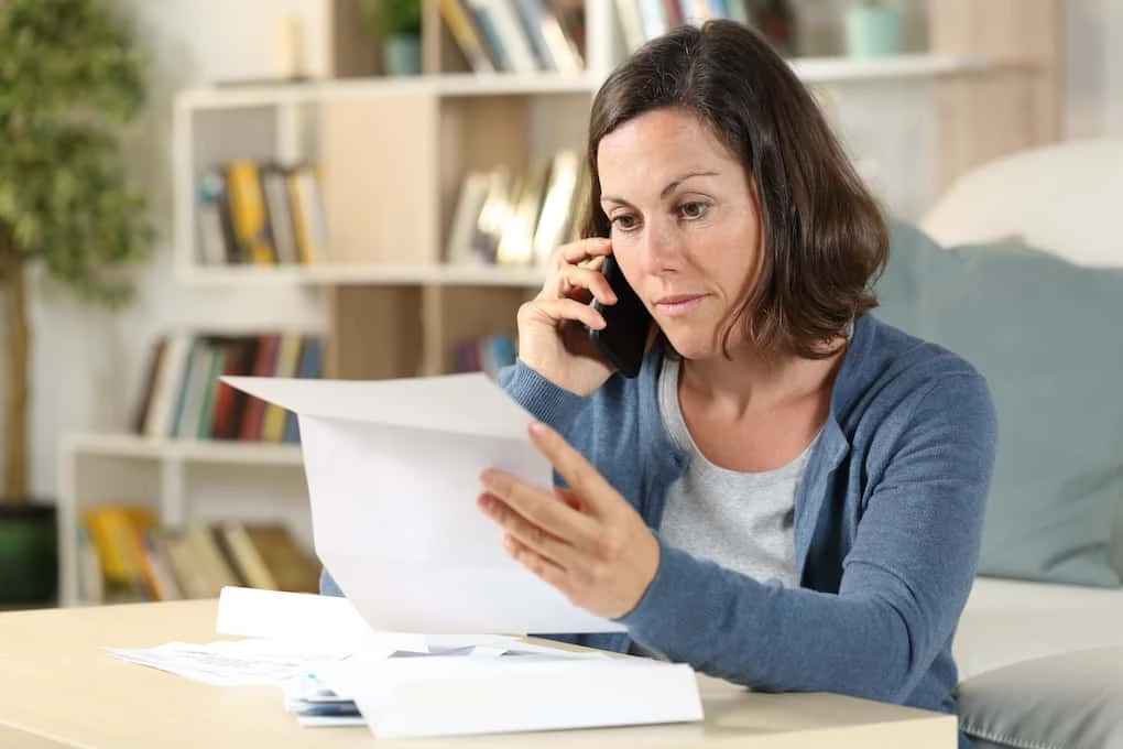 woman on phone looking over roofing insurance papers; roof depreciation