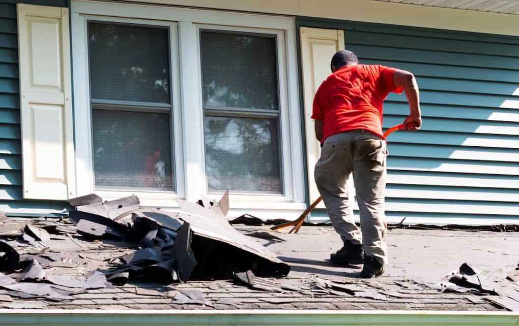 man removing old roofing to lower roof replacement costs