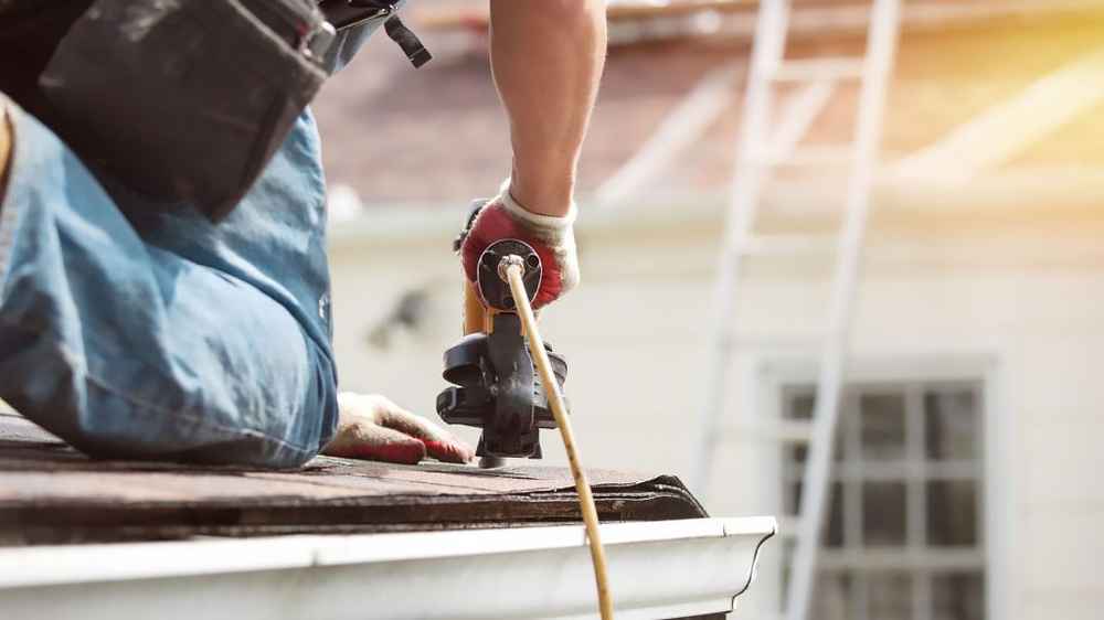 Roof repair in progress on a Maryland home with workers replacing damaged shingles